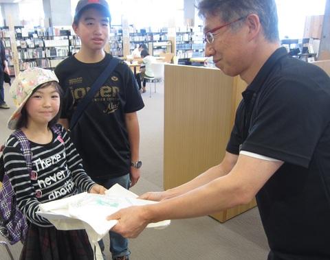 20万人目の来館者の方に小諸図書館オリジナルグッズの詰め合わせをお渡ししている写真