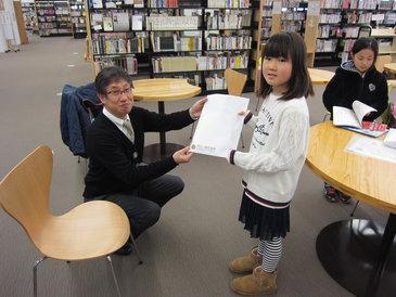 30万人目の来館者へ小諸図書館オリジナルグッズの詰め合わせをお渡ししている写真