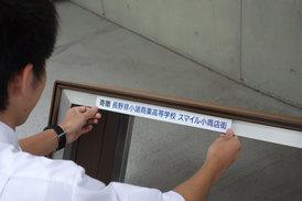 贈呈「長野県小諸商業高等学校 スマイル小商店街」のテプラシールをベンチに貼っている写真