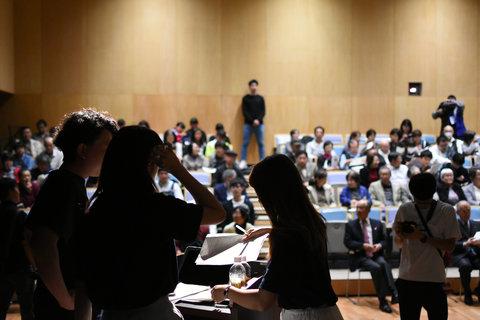 満席の会場にいる人々の写真